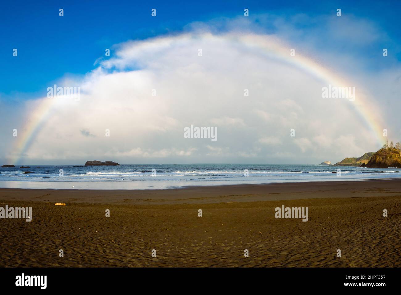 Rainbow over the ocean stretching from Pewetole Island out in to the sea.  Photographed at Trinidad State Beach, Trinidad, California, USA. Stock Photo