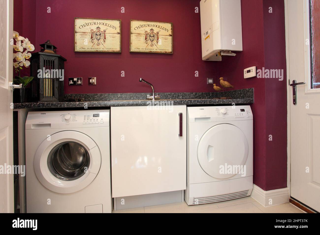 Utility room in modern new build house, washing machine, tumble dryer, dark pink purple feature walls. Stock Photo
