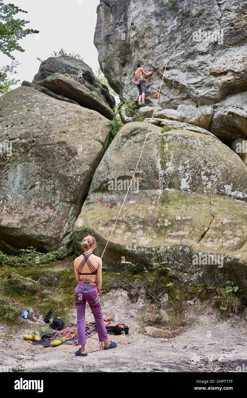 Female climber belaying leader during rock climbing outdoors, using