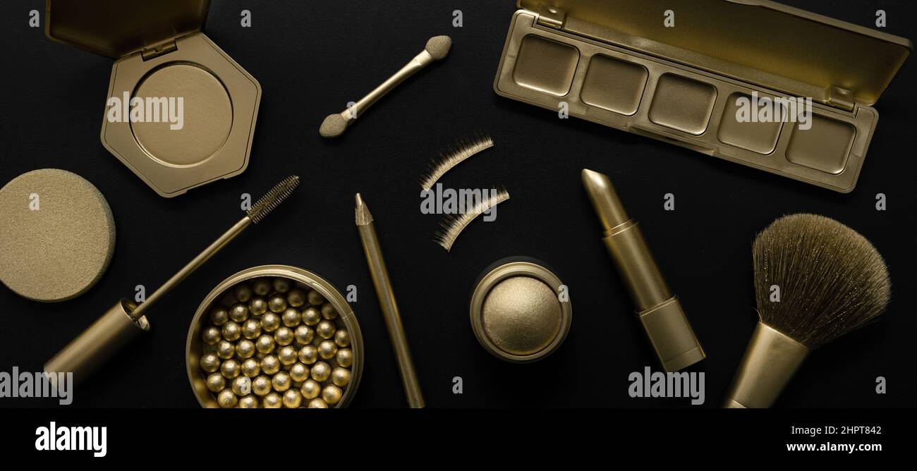 luxury cosmetics - set with golden makeup beauty products on black background. banner Stock Photo