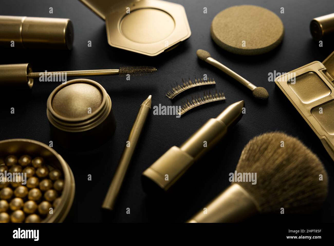 golden decorative makeup cosmetics on black table. luxury beauty products concept Stock Photo