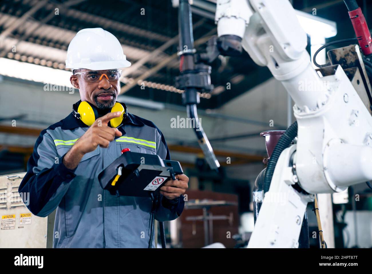 African American factory worker working with adept robotic arm in a