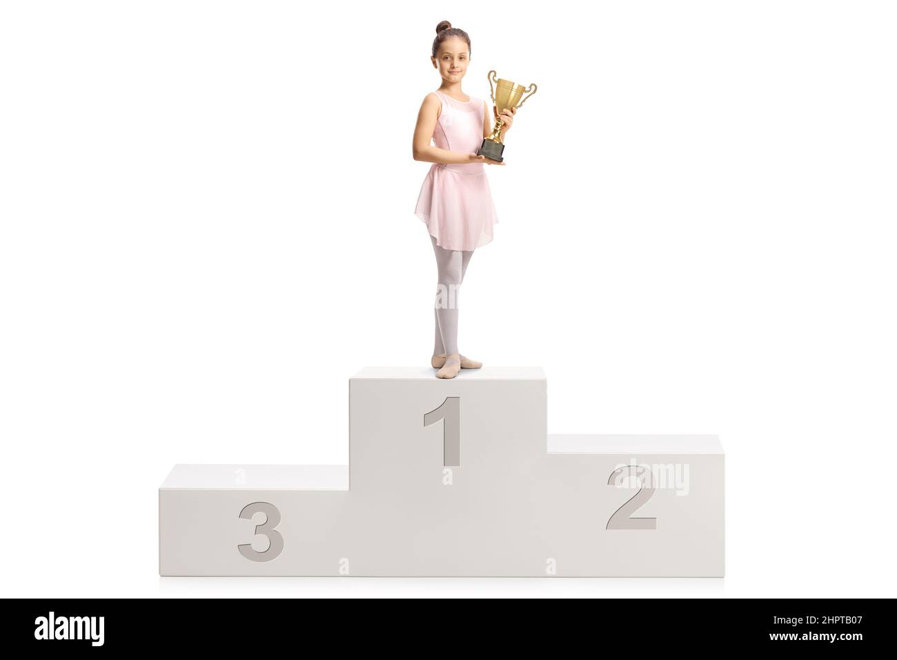 Ballerina in a pink dress holding a gold trophy cup on a winner podium isolated on white background Stock Photo