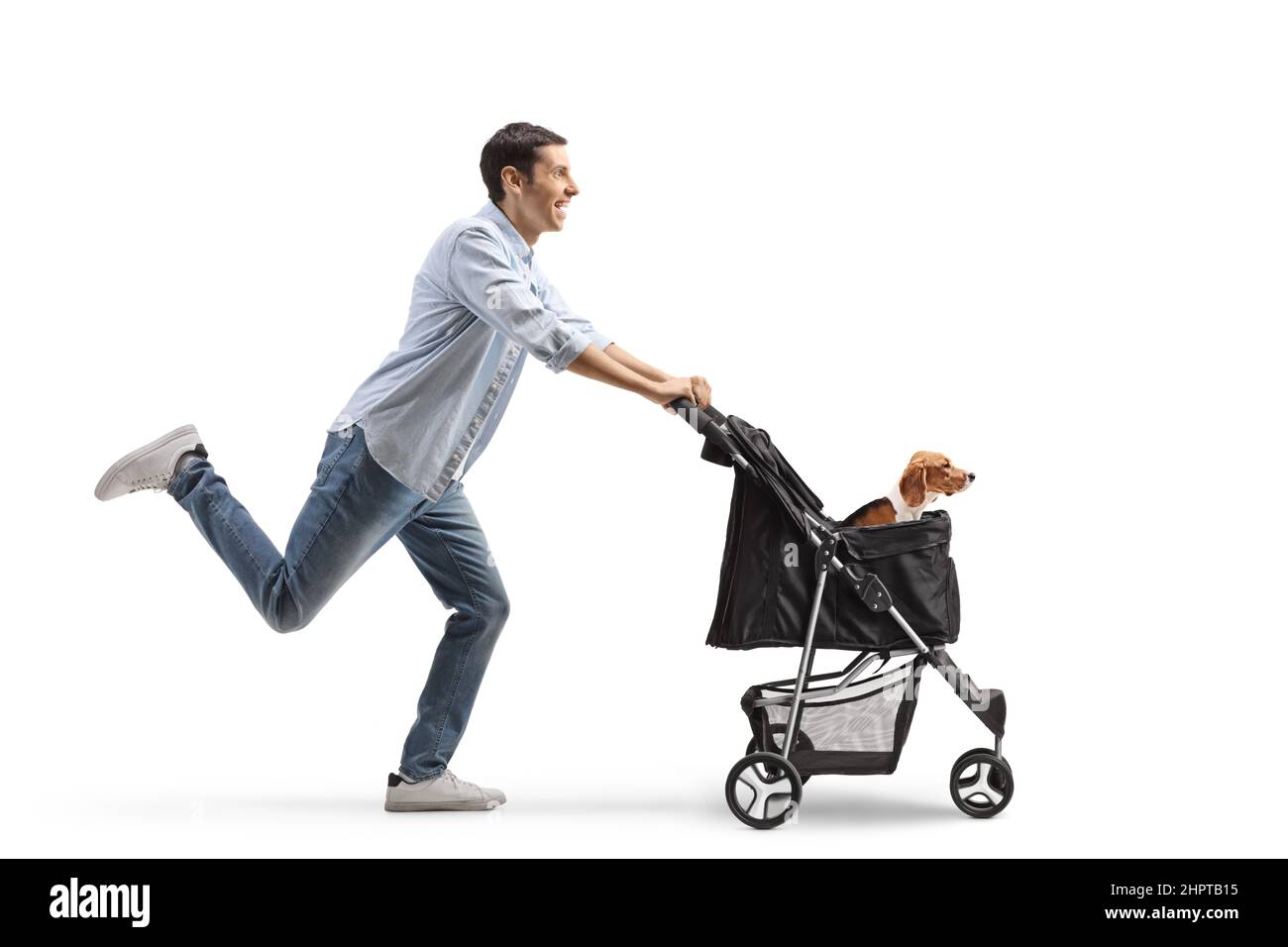 Full length profile shot of a casual young man pushing a dog stroller and running isolated on white background Stock Photo