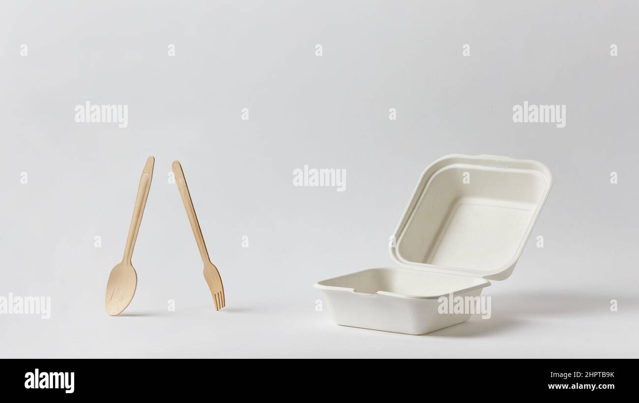 empty clean open white paper food box and wooden fork and spoon on