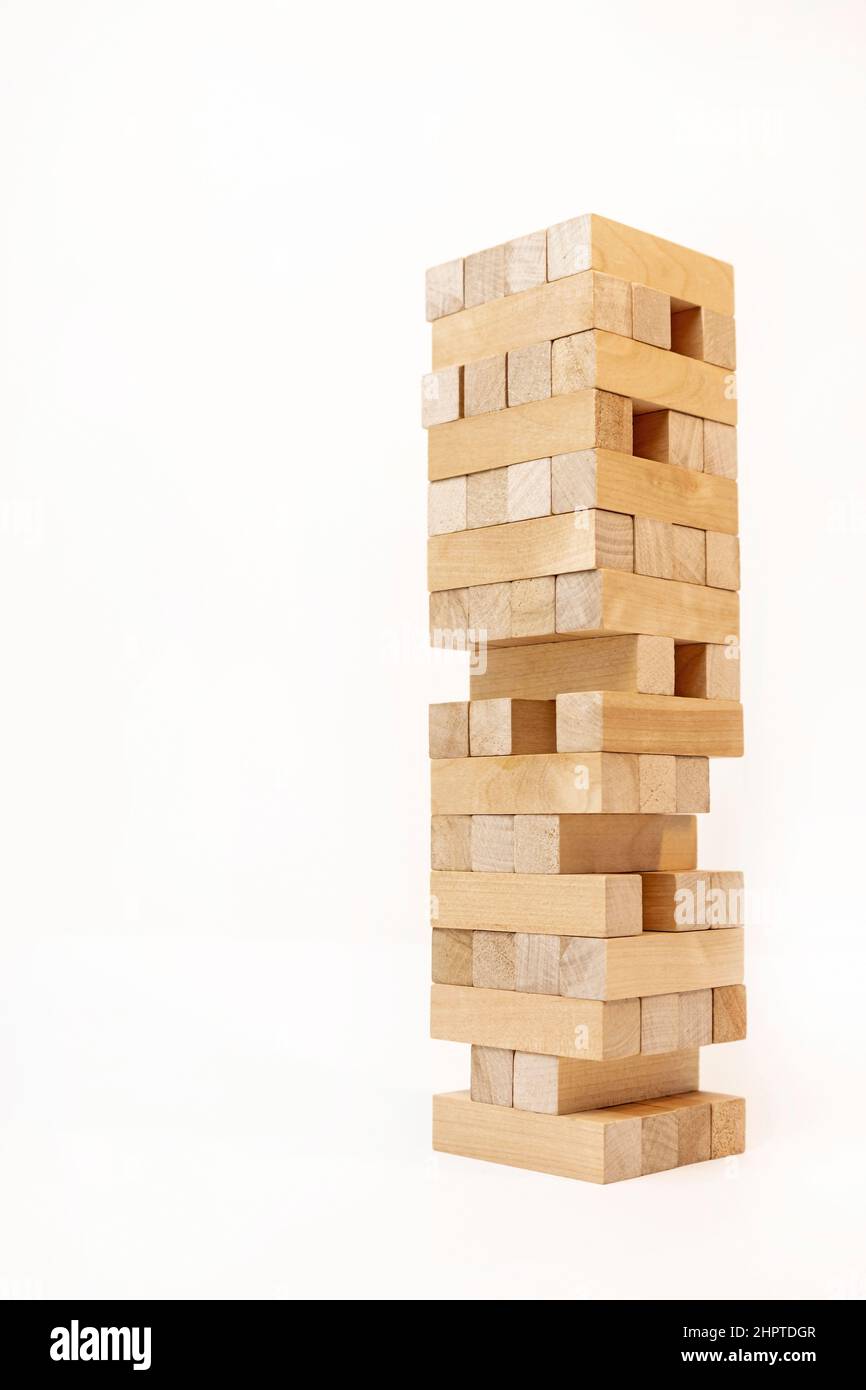 A game of logic and the ability to think. Jenga tower with wooden blocks on a white background. The tower is half dismantled. Stock Photo