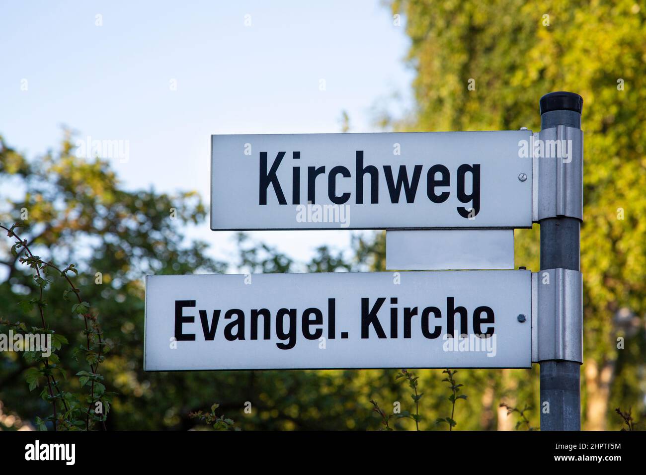 Street sign with the German text 'Kirchweg' and 'Evangel. Kirche' which tanslates into 'Churchway' and 'Protestant Church' in English language Stock Photo