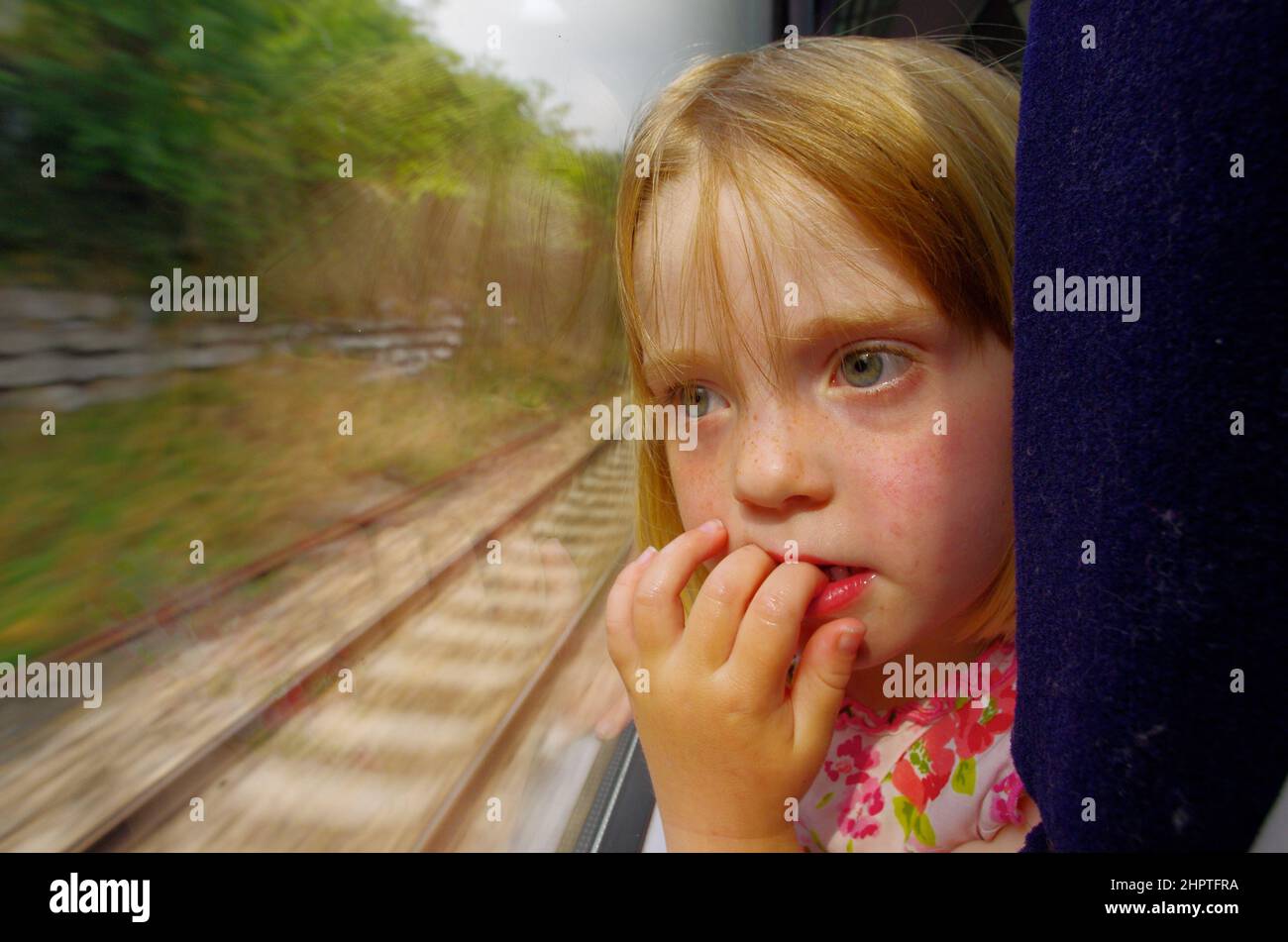 Sad child on train, looking out the window Stock Photo