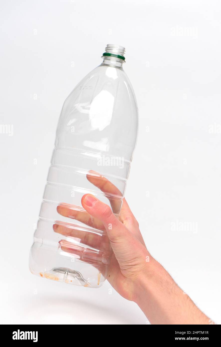 Hand holding a single use plastic drinks bottle ready for recycling photographed against a white