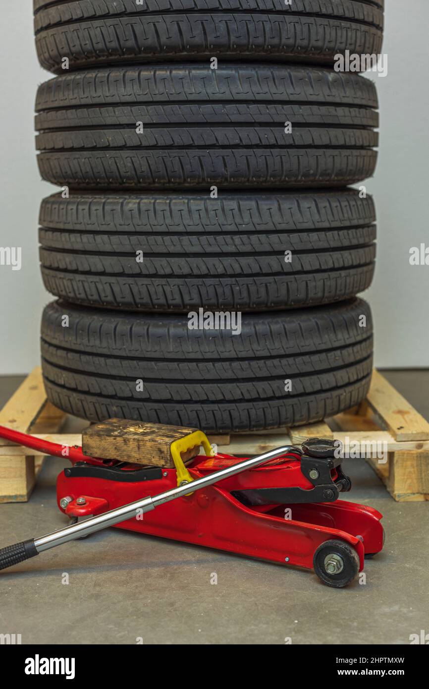 Close up view of car wheels lying on pallet with jack for changing