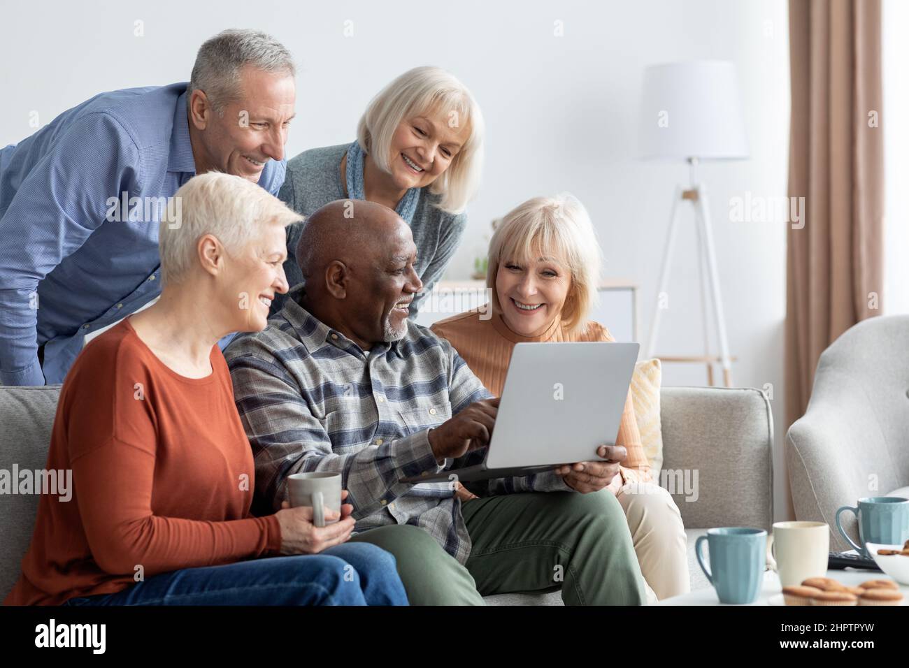 Positive elderly people spending time together at home, using gadgets Stock Photo
