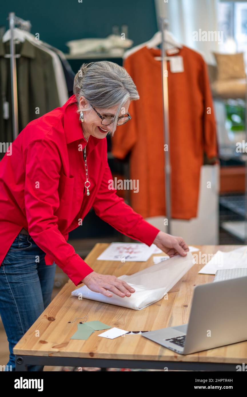 Satisfied woman packing clothes at table in store Stock Photo - Alamy