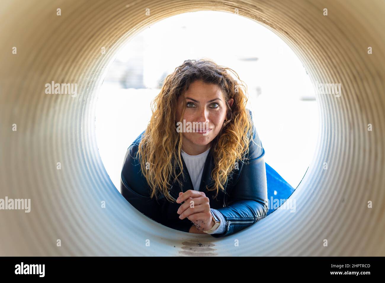 Caucasian woman posing from the inside of reinforced concrete pipes in the industrial area Stock Photo