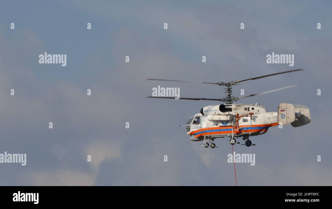 Moscow Russia AUGUST, 26, 2015 Helicopter with coaxial rotors with basket of water hanging from the barycentric hook to put out fires. Kamov Ka-32 helicopter of Russian Ministry for Emergency Stock Photo