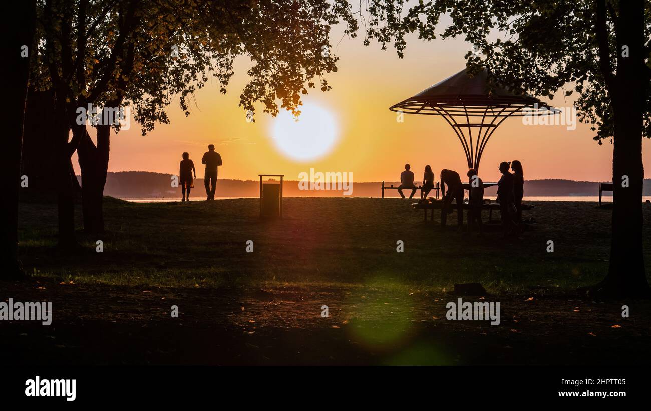 A serene summer sunset on the beach. Silhouettes of people walking in the evening Stock Photo