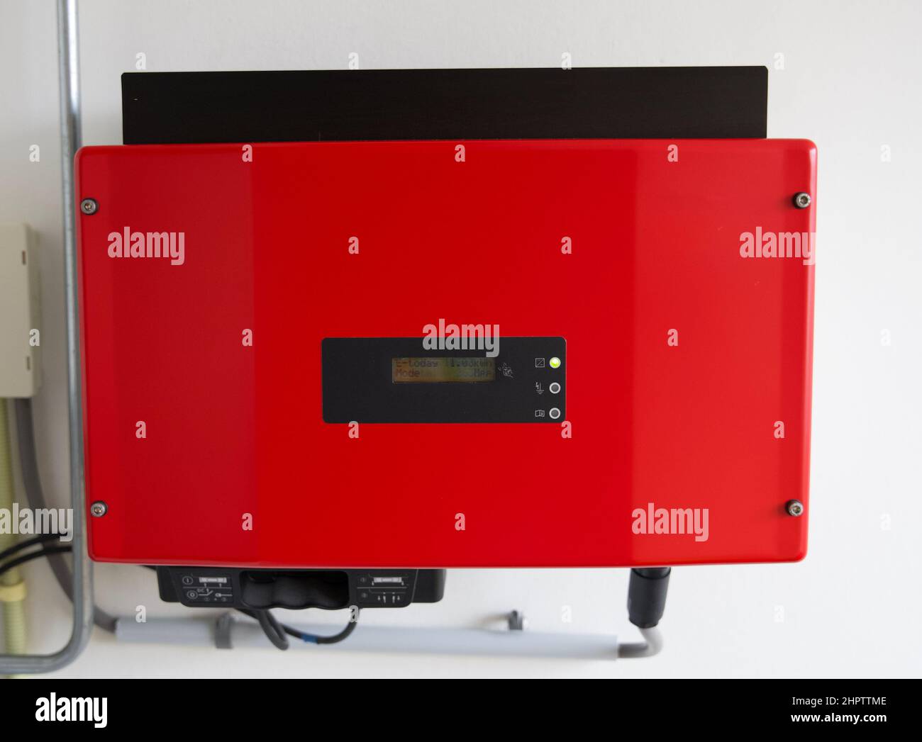 Close up of a red solar power inverter mounted to a white wall Stock Photo