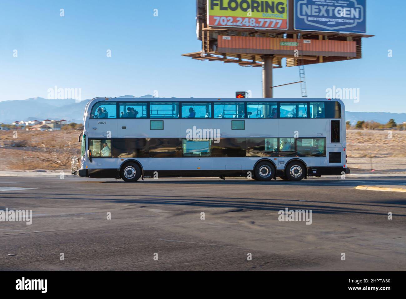 Las Vegas, NV, USA – February 17, 2022: A double decker white bus turning with driver and passengers wearing face mask in Las Vegas, Nevada. Stock Photo