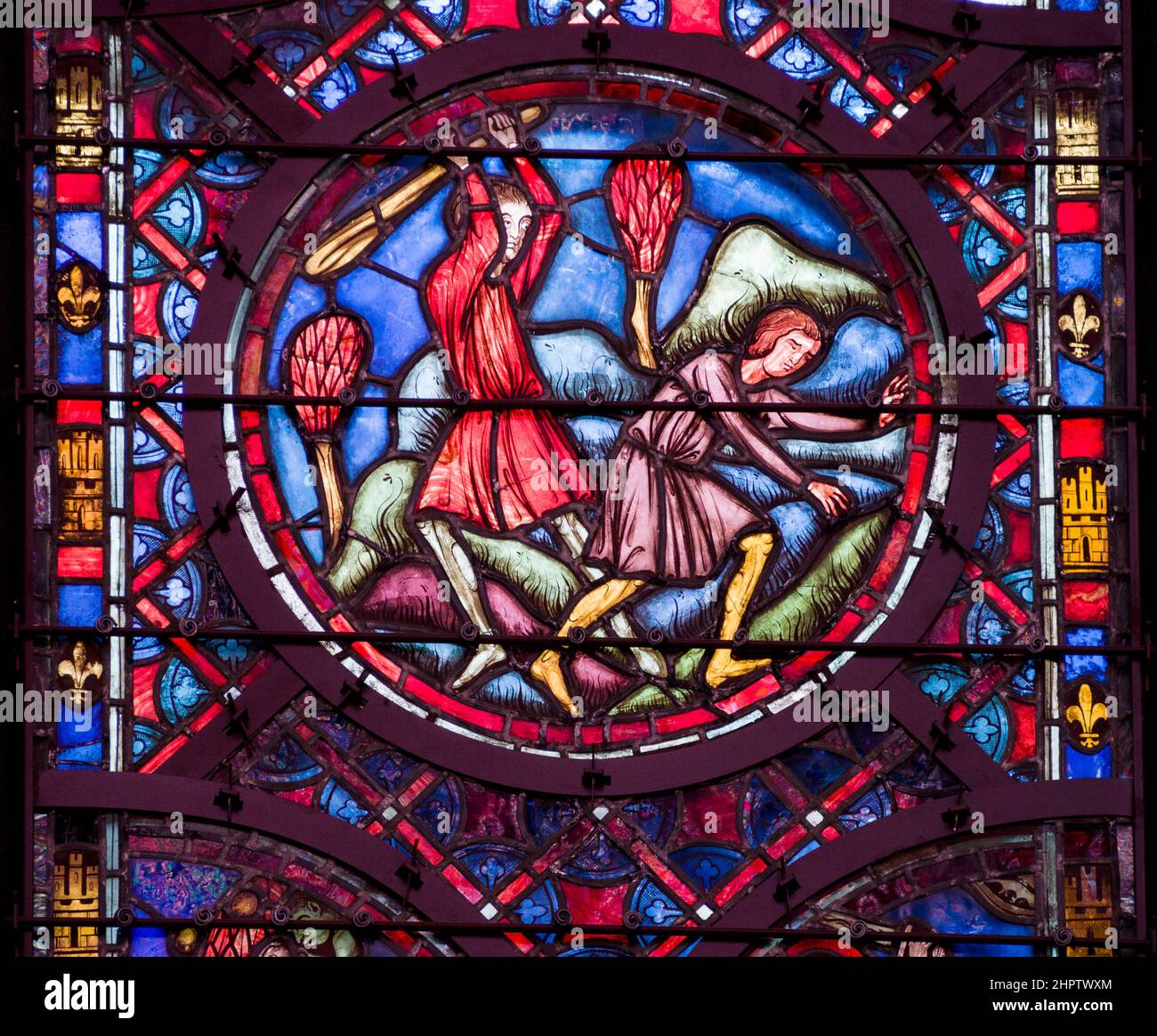 Fighting with a Bat in Stained Glass: Detail fom an ancient stained glass window in Sainte Chapelle. Two men fight with one holding a large bat ready to smash it over the other's back or head.. Stock Photo