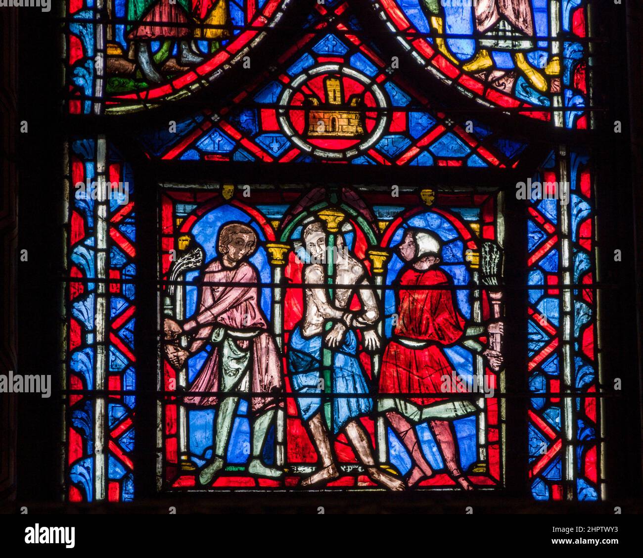 Punishment in Stained Glass: Detail fom an ancient stained glass window in Sainte Chapelle. A shackled man is whipped by two others while tied to a pillar. A castle hangs above. Stock Photo
