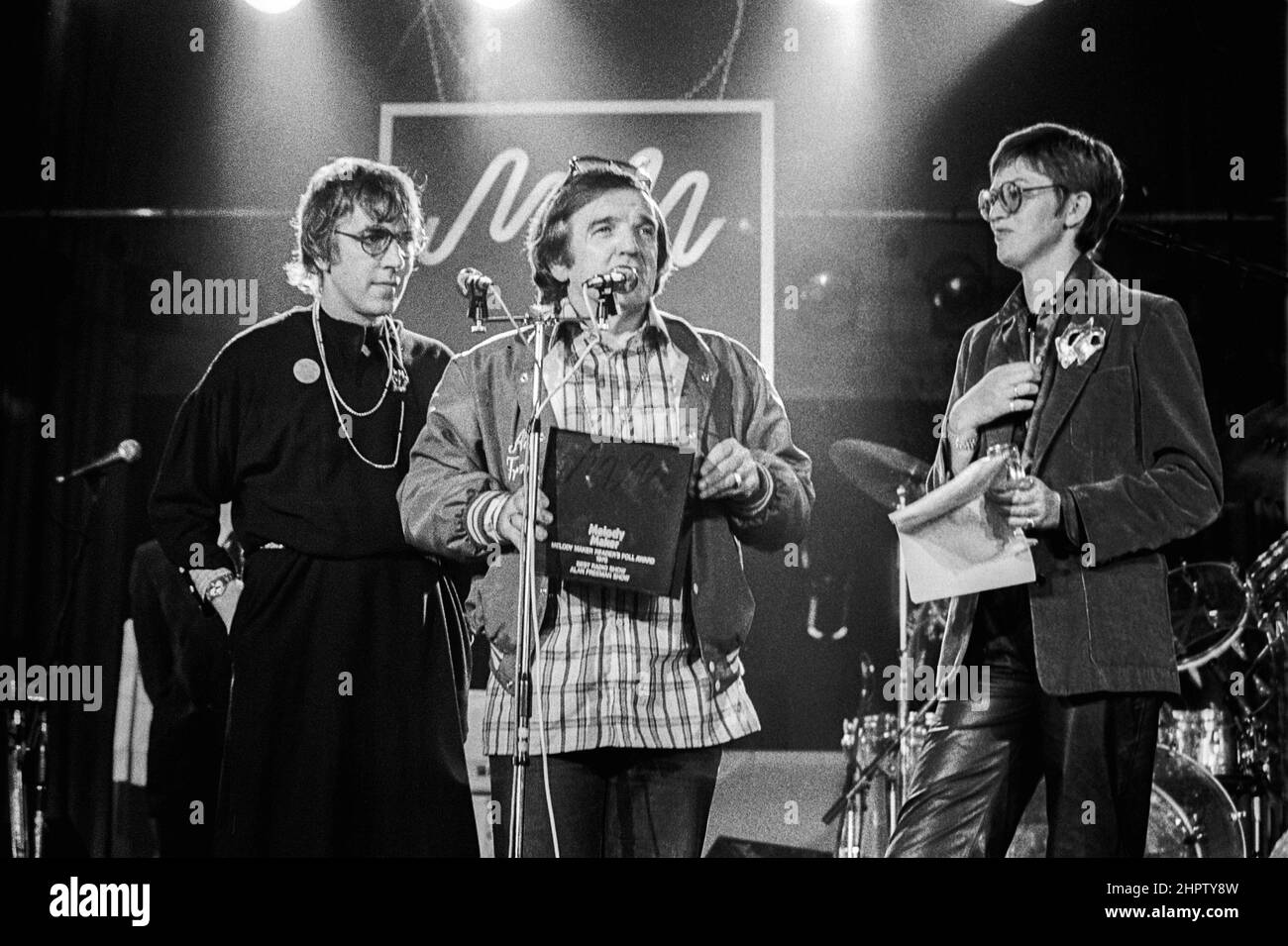 Australian DJ Alan 'Fluff' Freeman, MBE receiving an award from Peter Cook (wearing a dress) and Janet Street-Porter at a Melody Maker poll awards ceremony in London in 1979. Stock Photo