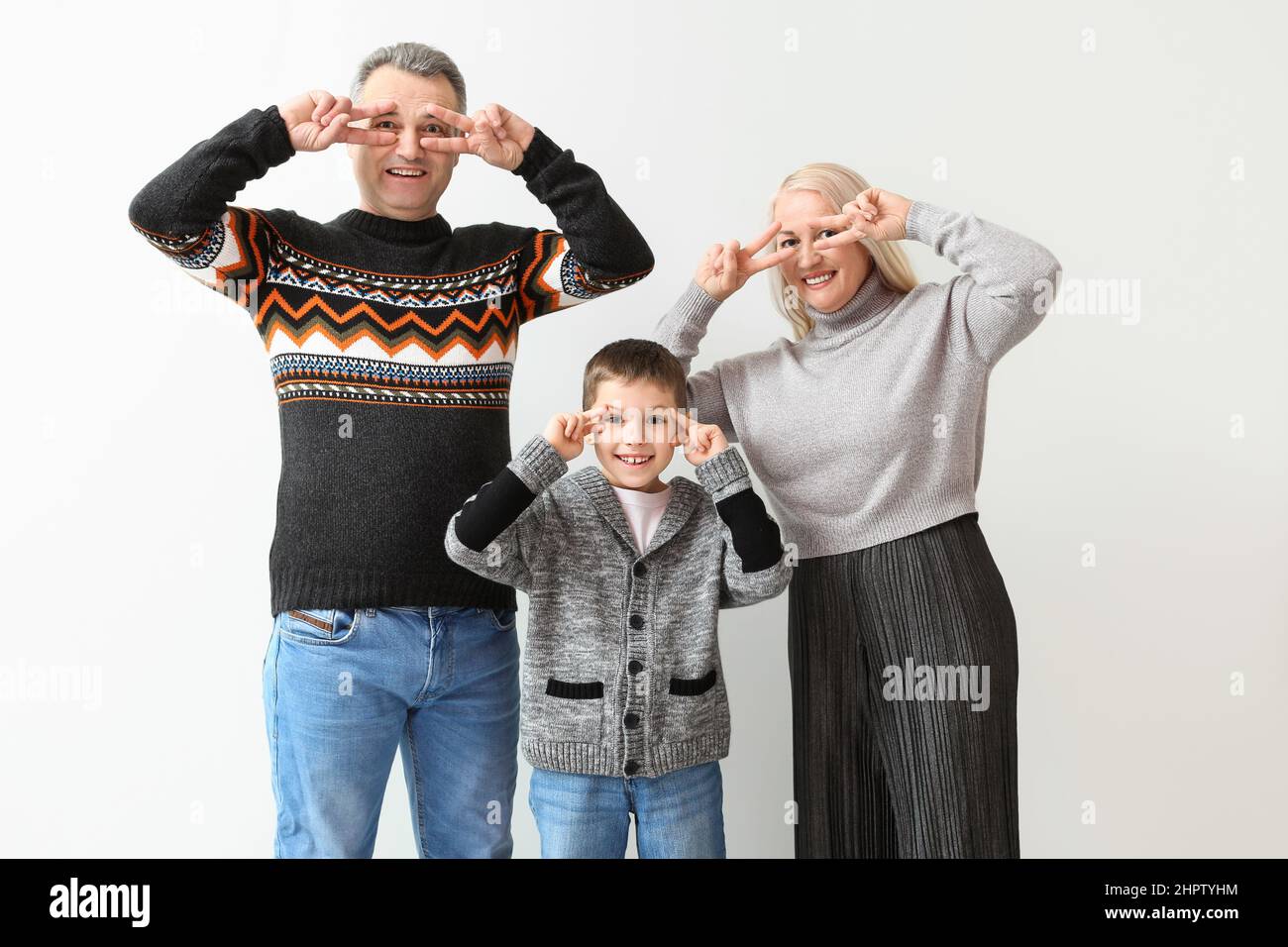 Little boy with his grandparents in warm sweaters dancing on light background Stock Photo