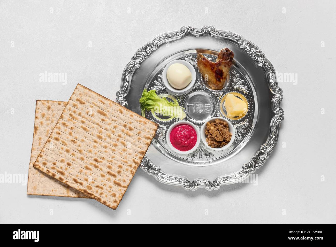 Passover Seder plate with traditional food and matza on white ...