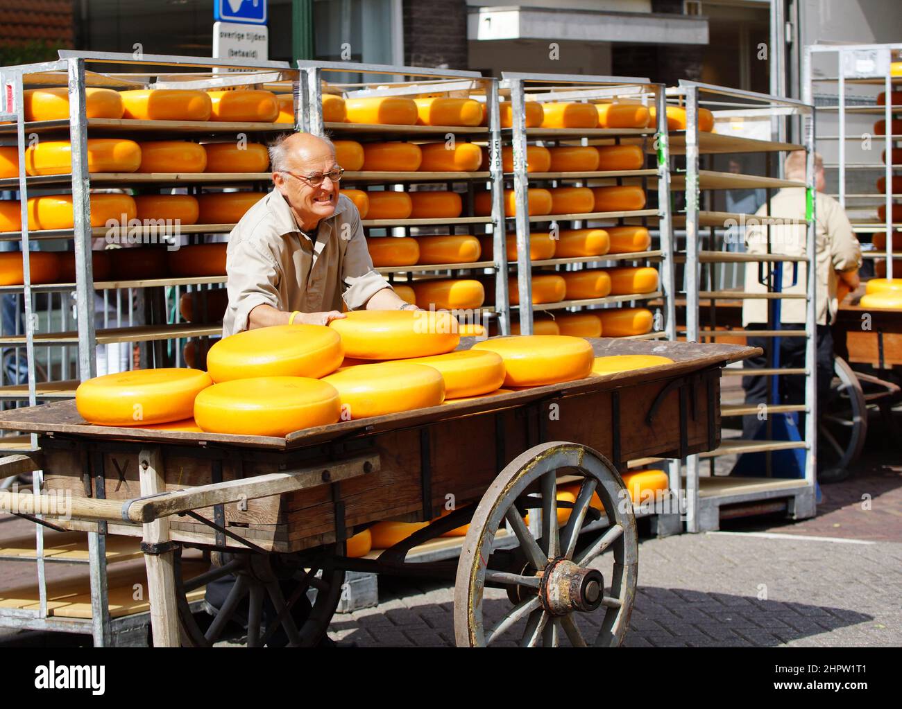 Man loading Gouda cheese in metal racks during a traditional event in