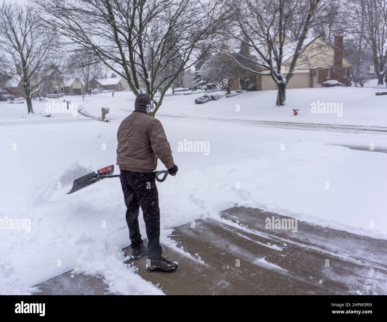 Old retiree clears snow off of driveway Stock Photo