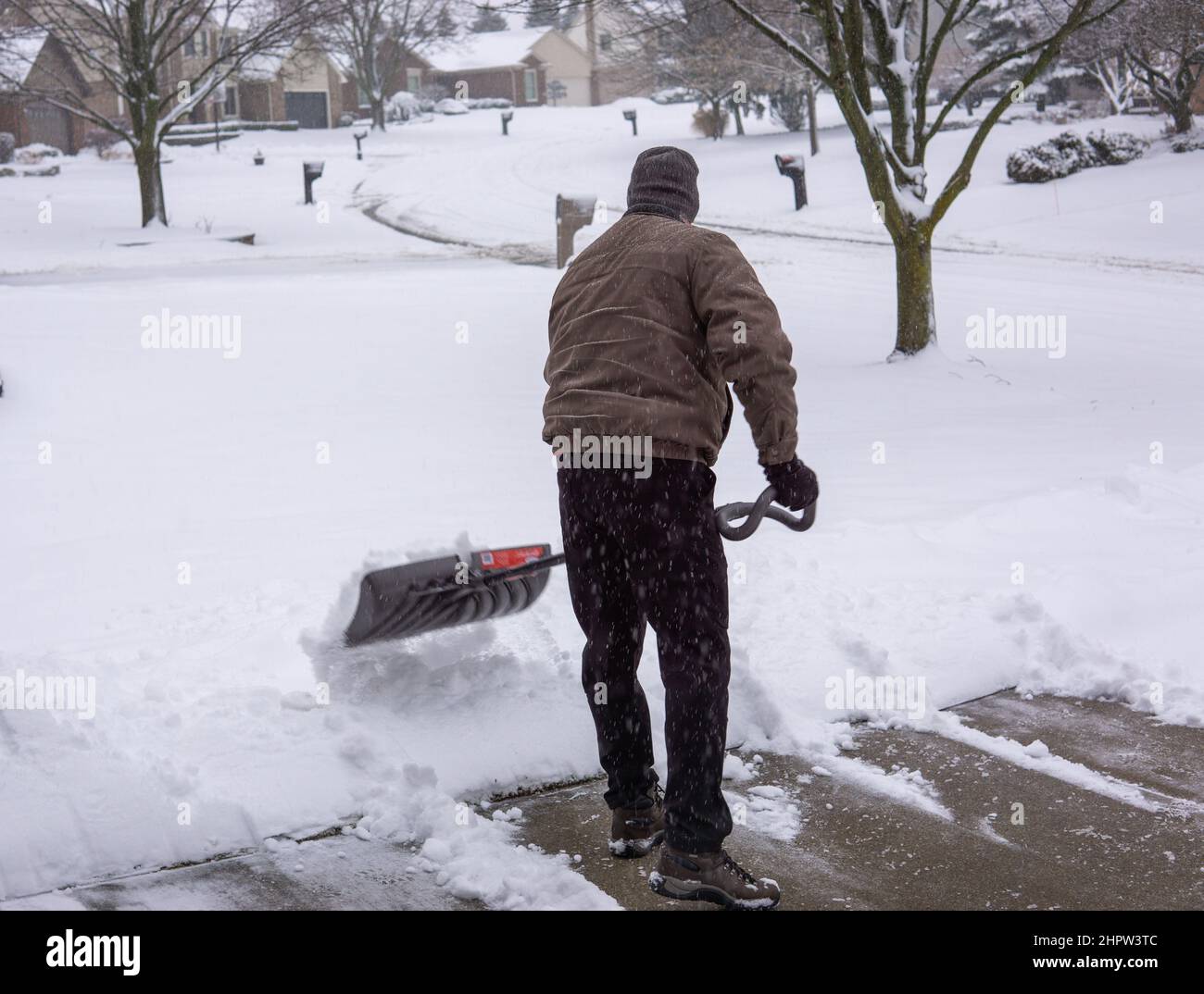 Man shoveling snow from driveway in winter back turned Stock Photo Alamy