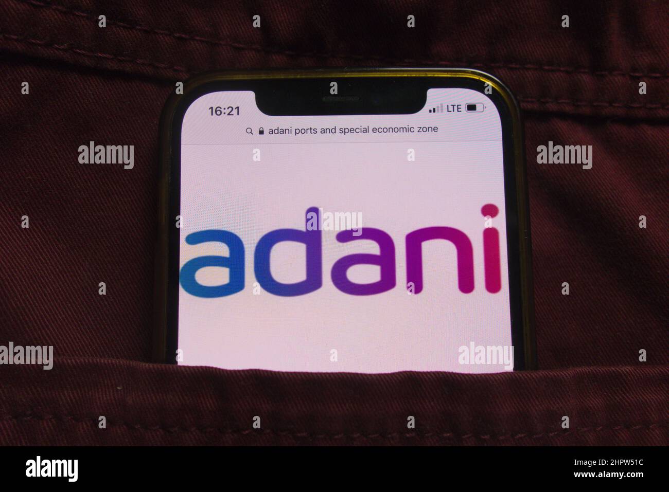 KONSKIE, POLAND - February 22, 2022: Adani Ports and Special Economic Zone Limited company logo displayed on mobile phone hidden in jeans pocket Stock Photo