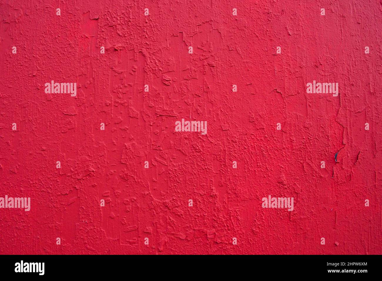 Texture of rough concrete wall covered and painted red decorative stucco. Background of blood-red colored plaster with cracks on concrete wall.  Stock Photo
