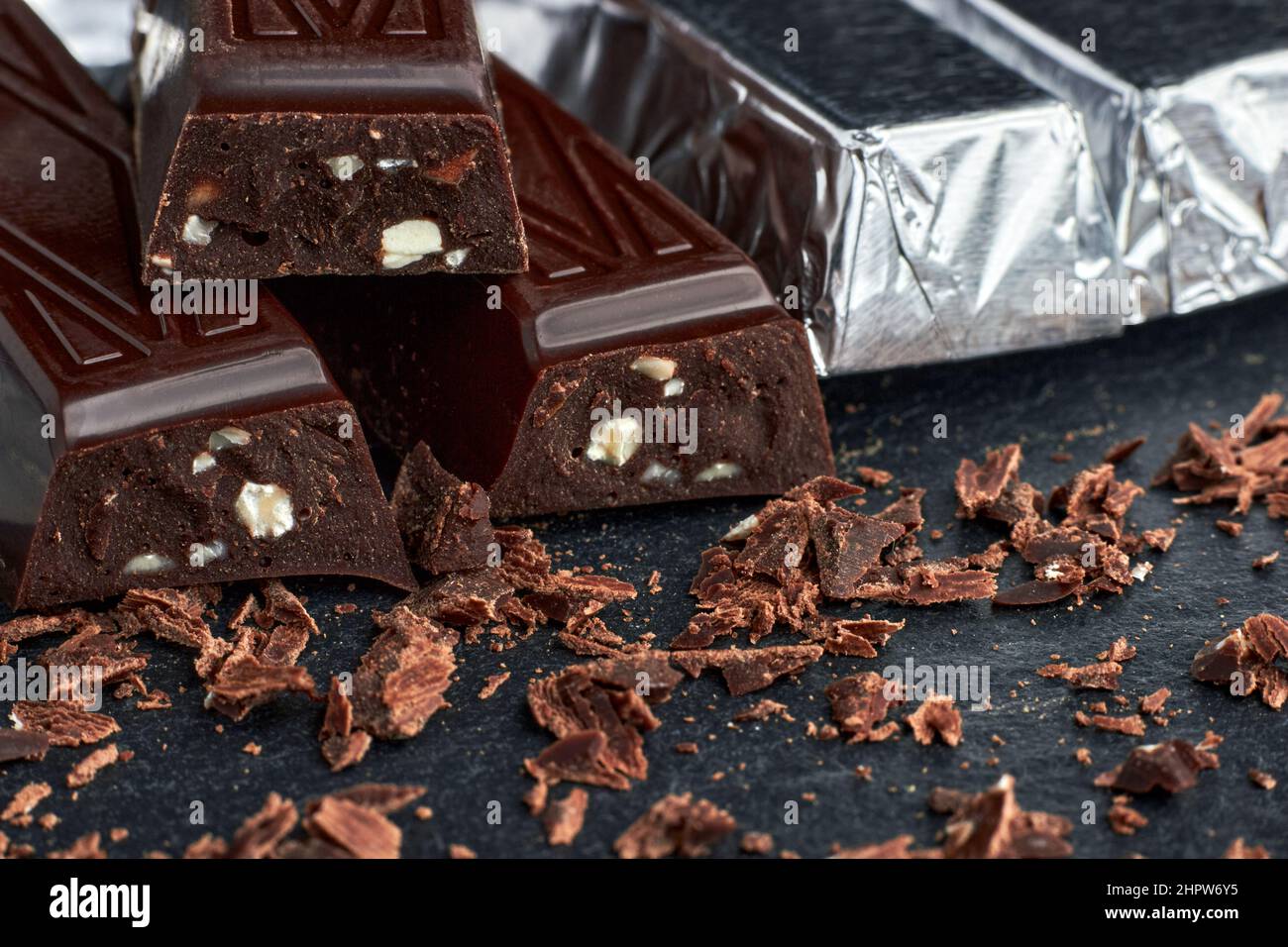Dark chocolate with chopped nuts wrapped in foil stacked and grated