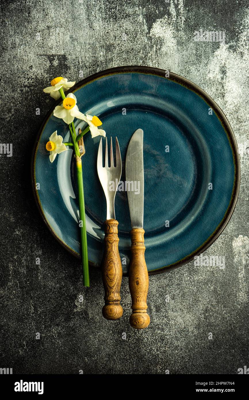 Minimalistic spring table setting decorated with fresh daffodil flowers on concrete background Stock Photo