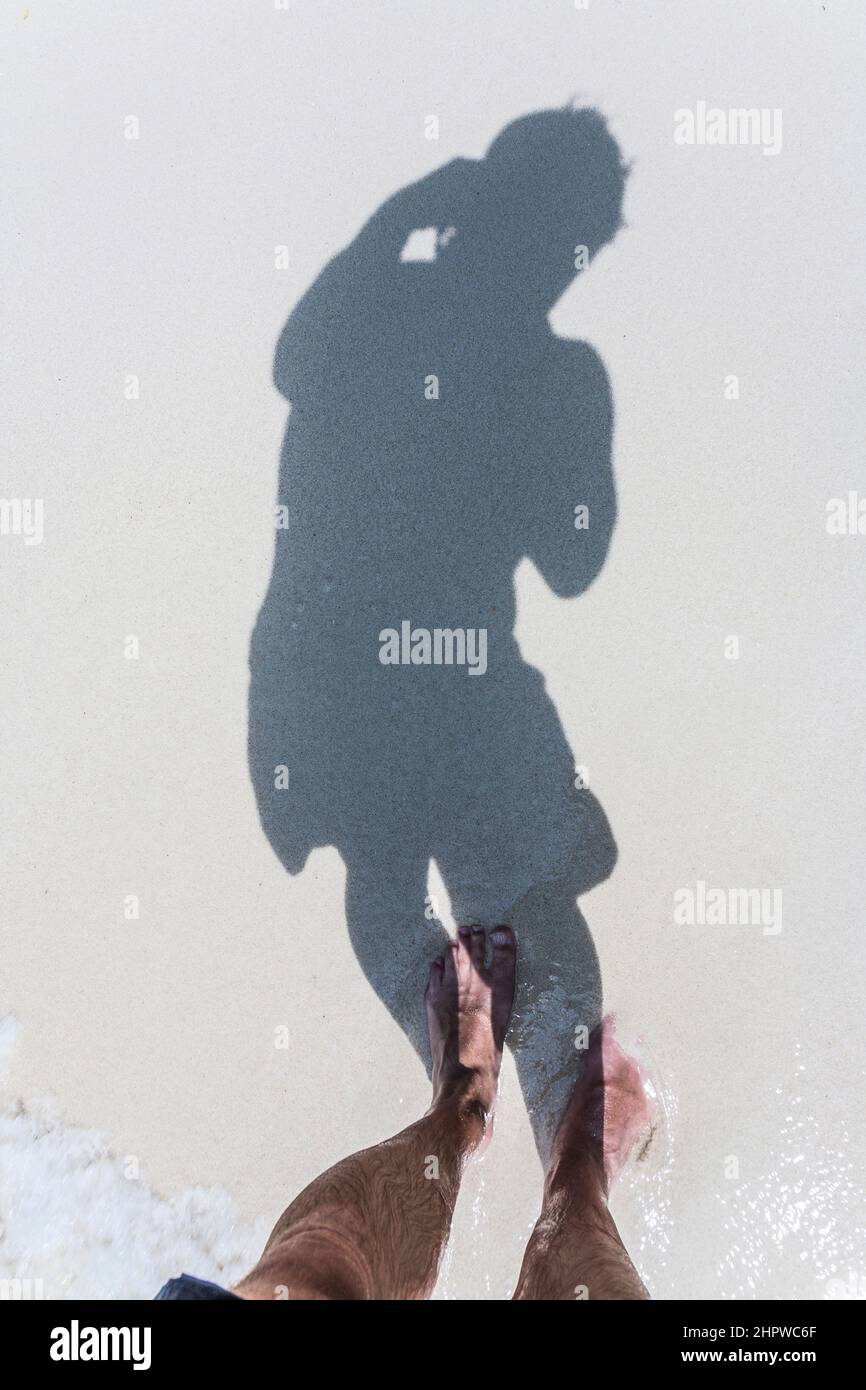 man is throwing shadow to the fine sand of the beach, showing the