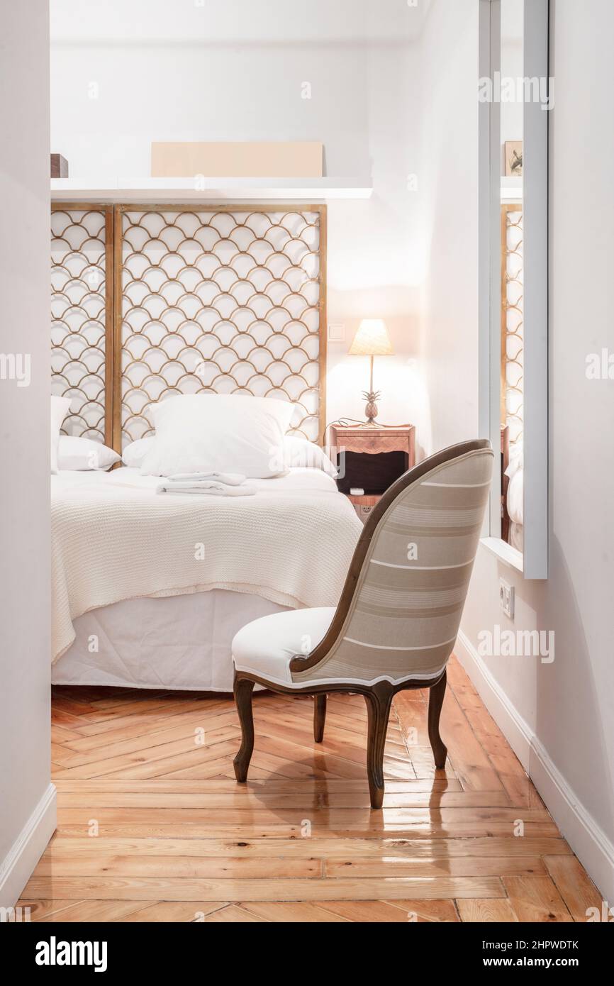 Bedroom with metallic gold headboard, upholstered armchair and wooden