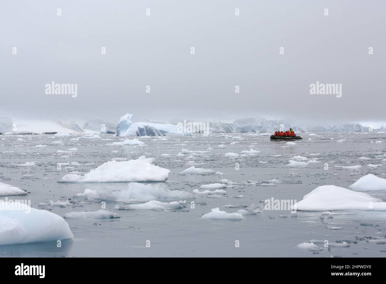 Cruise passengers from Le Boreal cruise ship traversing the ice strewn waters of Paradise Bay in a zodiac boat, just east of Bryde Island, Antarctica. Stock Photo