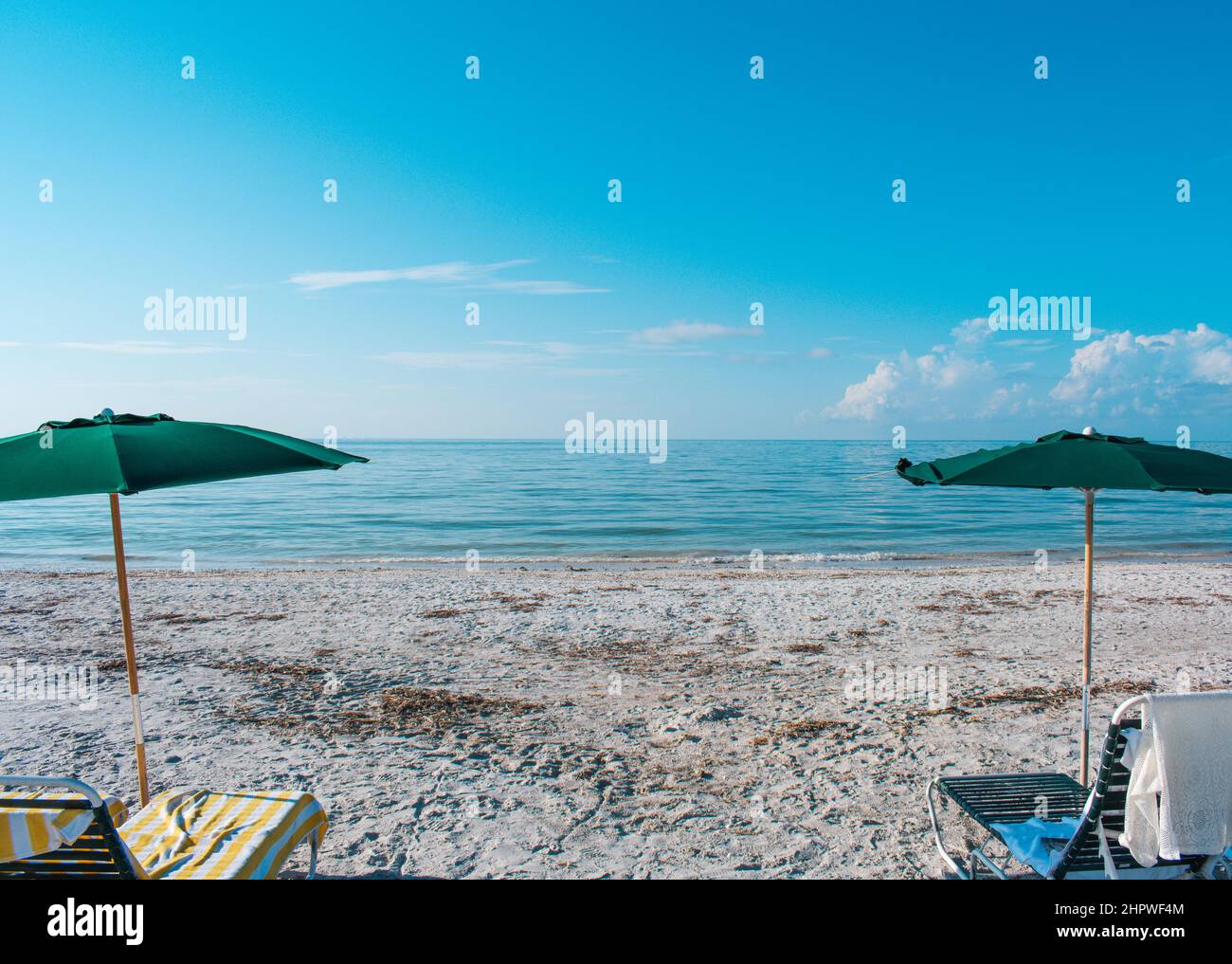 Sanibel Island beach framed by two umbrellas and lounge chairs Stock