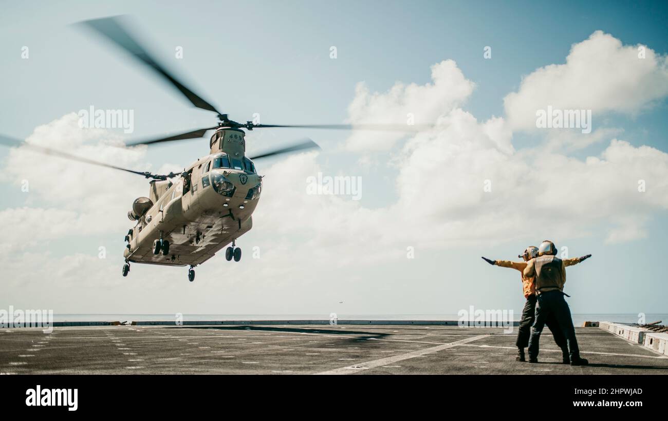 PACIFIC OCEAN (Feb. 18, 2022) U.S. Sailors assigned to amphibious transport dock USS Portland (LPD 27) signal a U.S. Army CH-47F Chinook attached to 3rd Battalion, 25th Aviation Regiment, 25th Combat Aviation Brigade, to land while conducting deck landing qualifications aboard Portland, Feb. 18. Marines and Sailors of the 11th Marine Expeditionary Unit and Essex Amphibious Ready Group are underway conducting routine operations in U.S. 3rd Fleet. (U.S. Marine Corps photo by Gunnery Sgt. Donald Holbert) Stock Photo