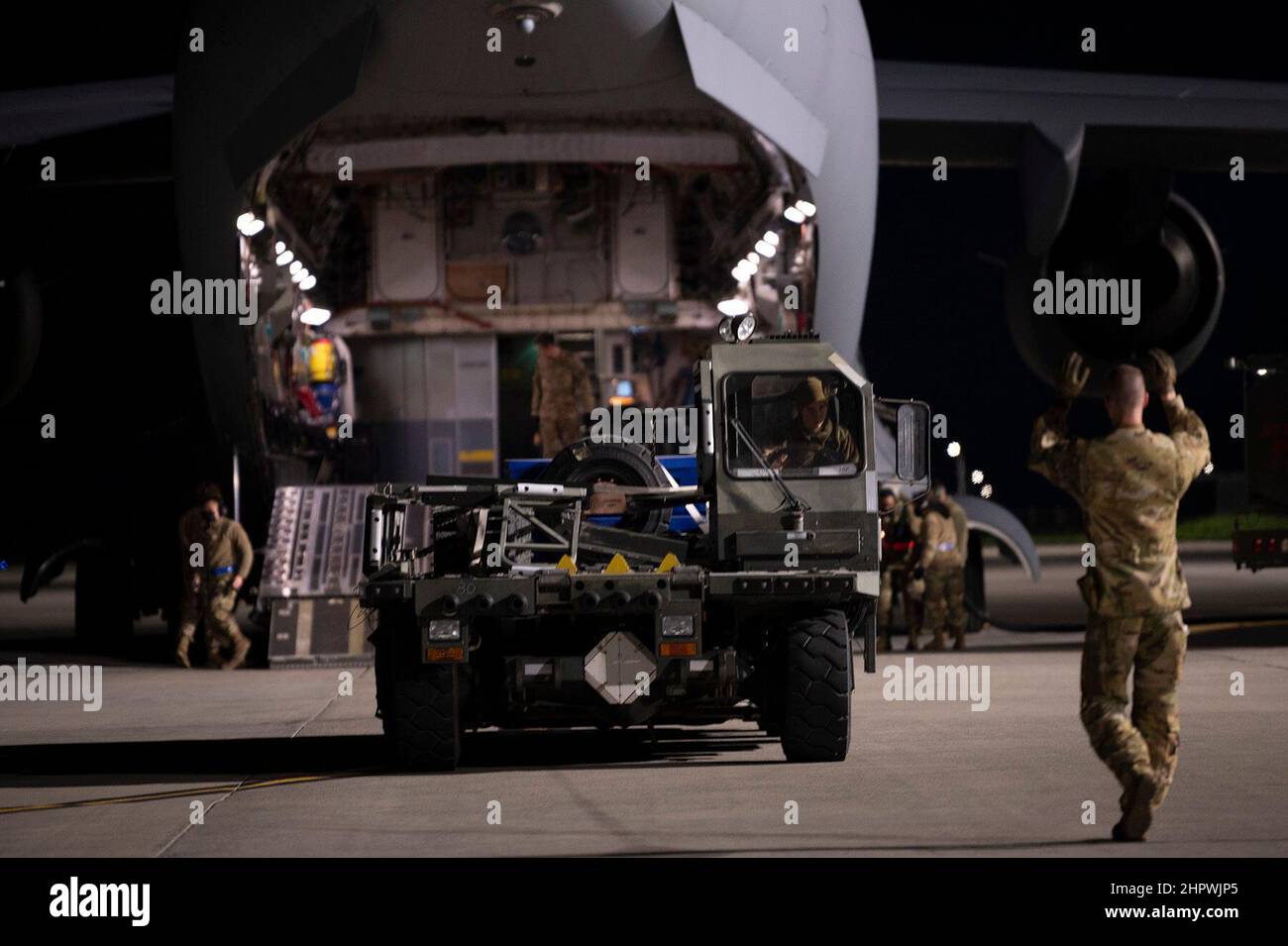 U.S. Air Force Airman 1st Class Chase Smith, right, 8th Airlift Squadron loadmaster, marshals a K-loader toward a C-17 Globemaster III, assigned to Joint Base Lewis-McChord, Washington, at Travis Air Force Base, California, Feb. 14, 2022. U.S. Airmen with the 60th Aerial Port Squadron and 8th Airlift Squadron load K-loaders onto the C-17. K-loaders are used to transport cargo into and out of aircraft. Under the direction of U.S. Transportation Command, the 60th Air Mobility Wing supported the 621st Contingency Response Wing during the movement of security assistance cargo to Ukraine via commer Stock Photo