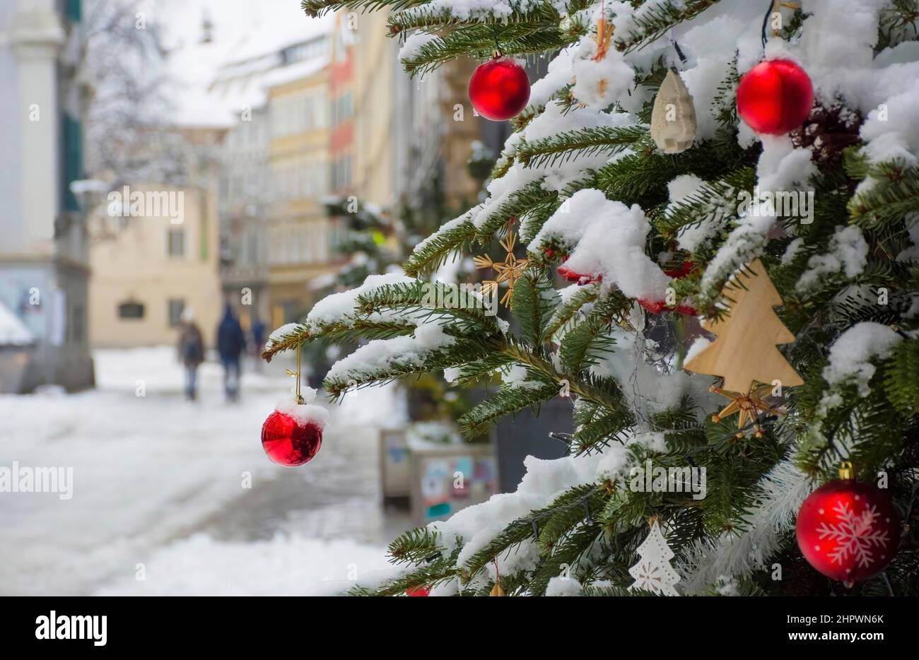 Beautiful Christmas tree detail and blurred people walking through the snow in winter day, in the city center of Graz, Steiermark, Austria. Selective Stock Photo
