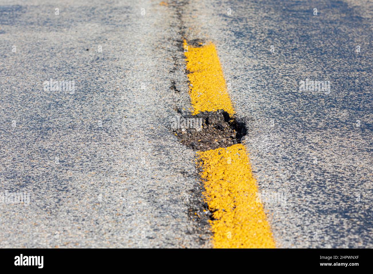 Closeup of pothole, chuckhole, in asphalt pavement road. Street repair, maintenance and damage concept. Stock Photo
