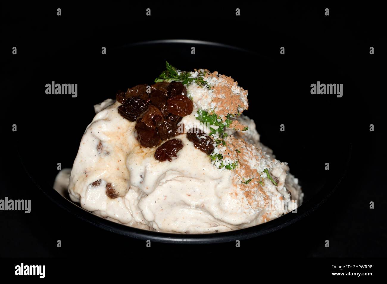 Rum, sultanas, coconut ice cream with cinnamon and fresh mint, studio photography with black background Stock Photo