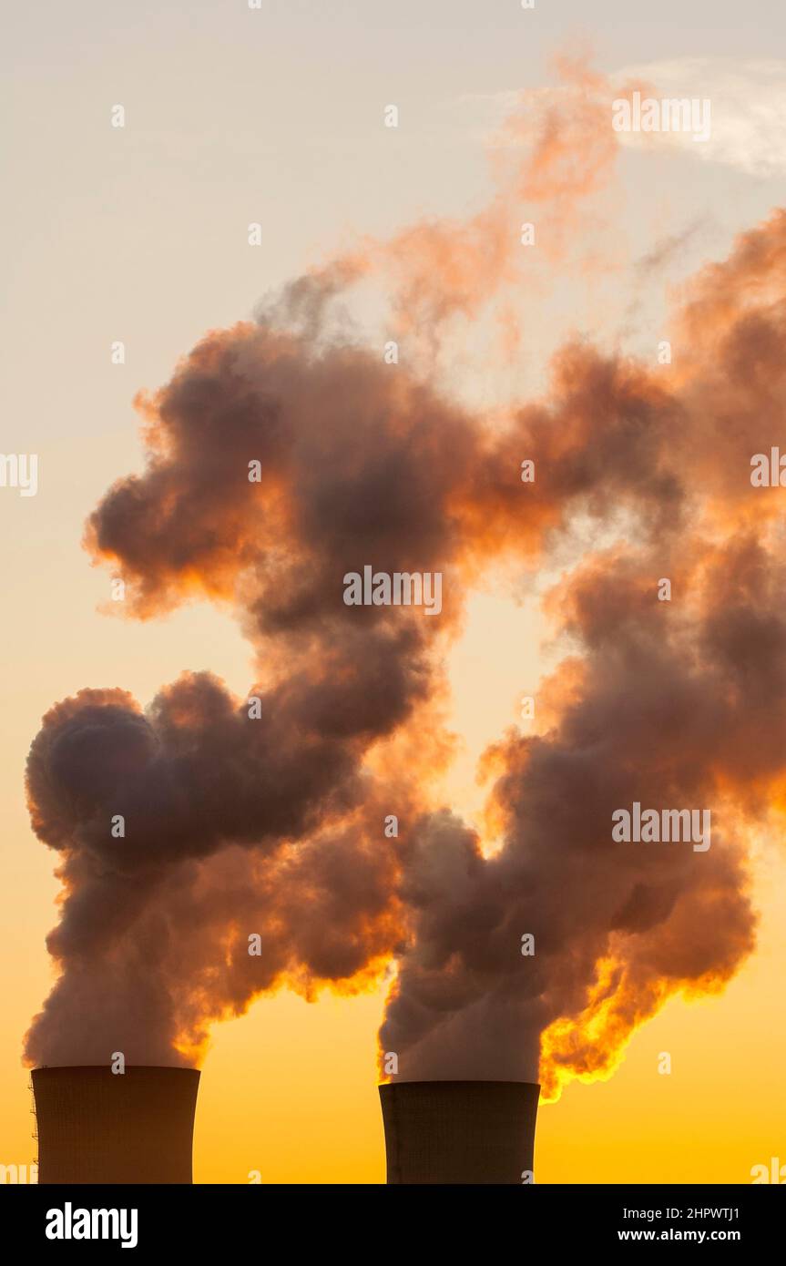 Nuclear power plant, cooling towers and backlit water vapour, evening