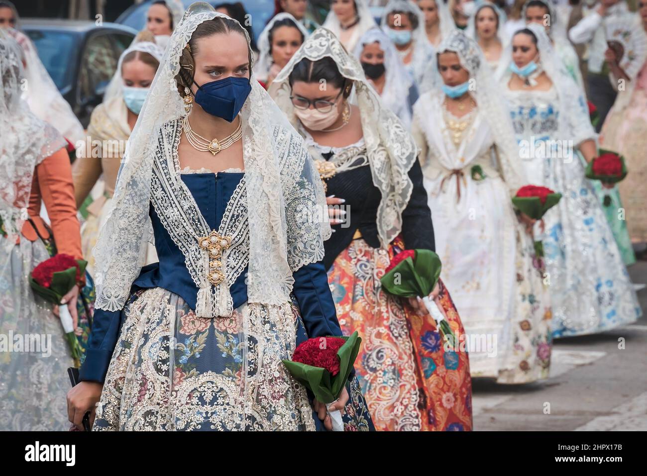 Valencia, Spain - 4 September 2021: Women with face masks for covid protection and traditional floral dresses walking for the parade at the celebratio Stock Photo