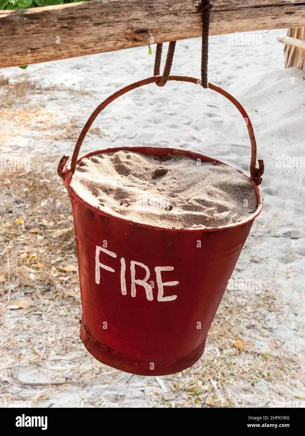 red sand bucket painted in red with fire sign and sand to extinguish fire Stock Photo