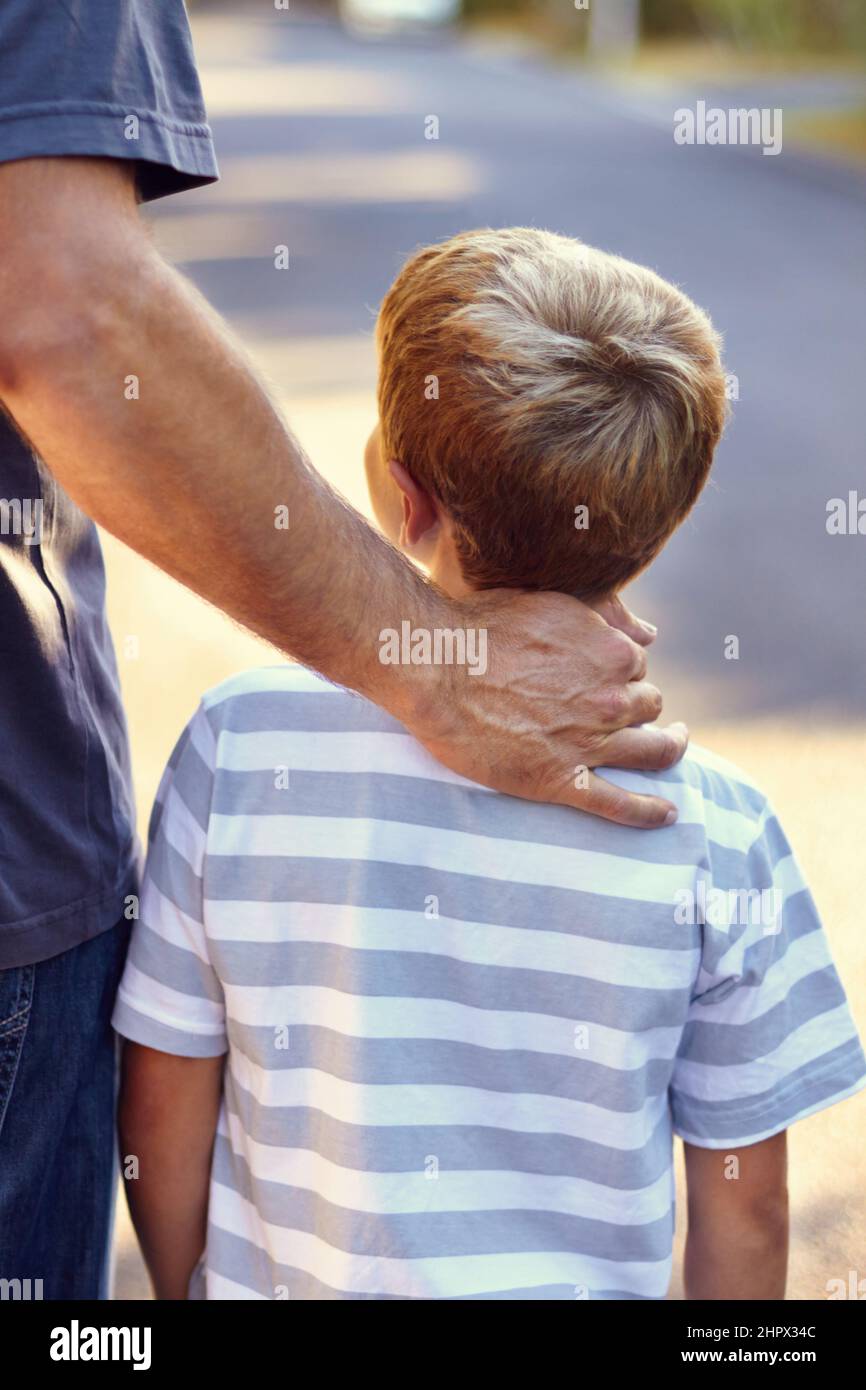 The guiding hand of a caring father. Rearview shot of a father and son walking down the street together. Stock Photo