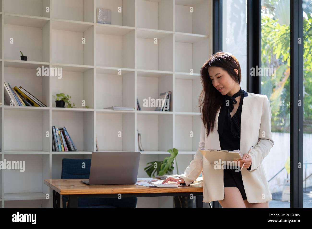 Attractive asian woman checking taxes, bank account balance and calculating expenses in the living room at home Stock Photo