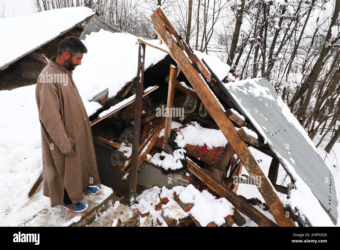 Budgam, India. 22nd Feb, 2022. A house owner inspects his damaged house at Bugam Chadoora village. Kashmir valley received heavy snowfall, leading to the closure of roads in far-flung areas besides the delay of several flights operating from the Srinagar airport. The local train services have also been suspended. Credit: SOPA Images Limited/Alamy Live News Stock Photo