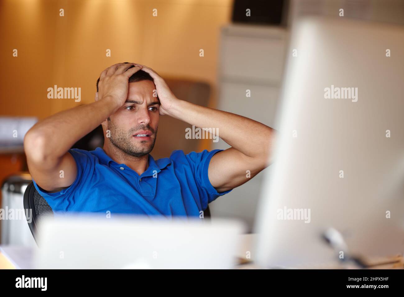 What have I done. Shot of an attractive young man looking worried at his desk. Stock Photo