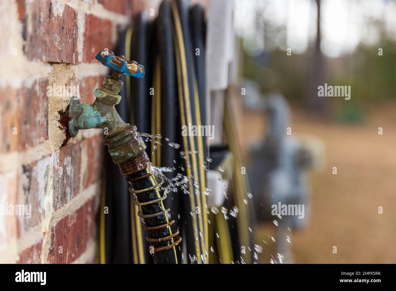 Water leaking from hose attached to faucet Stock Photo